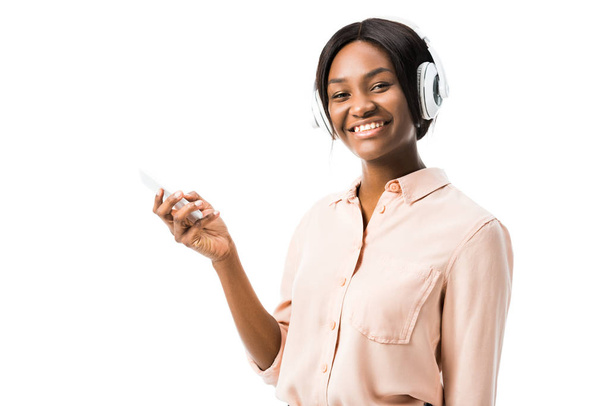 mosolygós afro-amerikai nő ing fejhallgató gazdaság okostelefon elszigetelt fehér  - Fotó, kép
