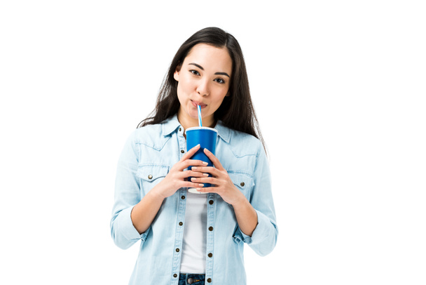 attractive asian woman in denim shirt drinking from plastic cup isolated on white  - Foto, imagen