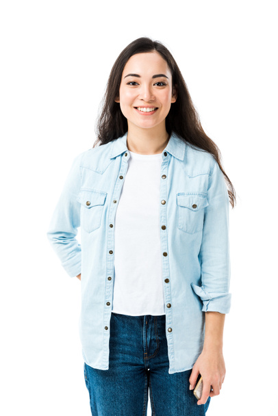 attractive and smiling asian woman in denim shirt looking at camera isolated on white  - Foto, Imagem