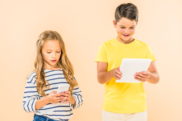 two kids using smartphone and digital tablet isolated on pink - Photo, image