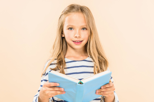 front view of smiling child holding book isolated on pink - Photo, image
