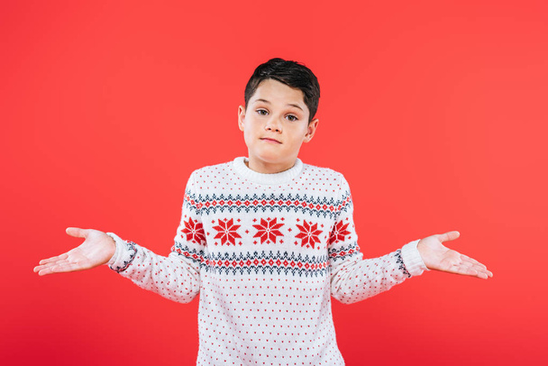 front view of child in sweater showing shrug gesture isolated on red - Foto, Bild