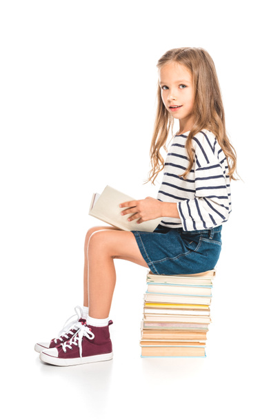 kid in denim skirt sitting on books and reading on white - Foto, afbeelding