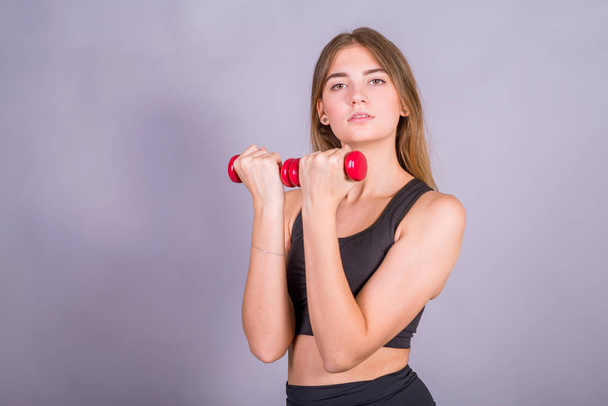 Portrait of pretty sporty girl holding weights. - Фото, зображення