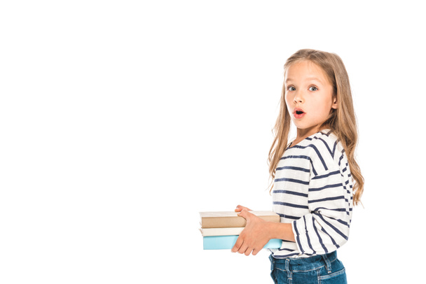 σοκαρισμένος παιδί κρατώντας βιβλία με ανοιχτό στόμα απομονωμένο σε λευκό - Φωτογραφία, εικόνα