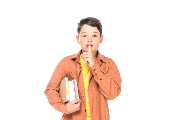 front view of kid holding books and showing hush gesture isolated on white - Φωτογραφία, εικόνα