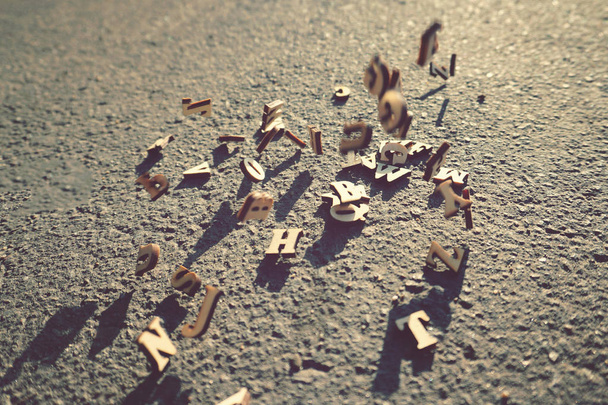 Letters vallen op het asfalt, getinte foto van het Engelse alfabet, leren en wetenschap. - Foto, afbeelding