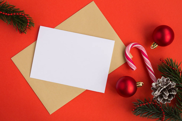Порожній білий папір для тексту, конверта та різдвяної композиції на червоному тлі. Перегляд згори. Простір для копіювання
. - Фото, зображення
