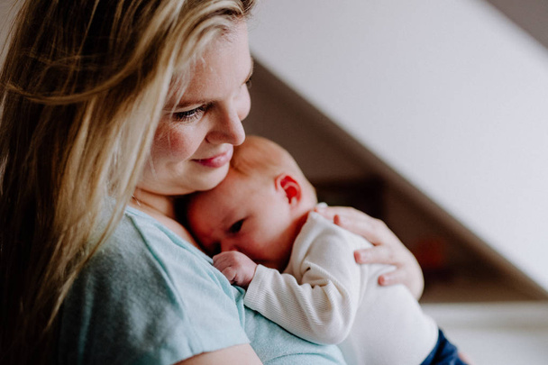 eine schöne junge Mutter mit einem Neugeborenen zu Hause. - Foto, Bild