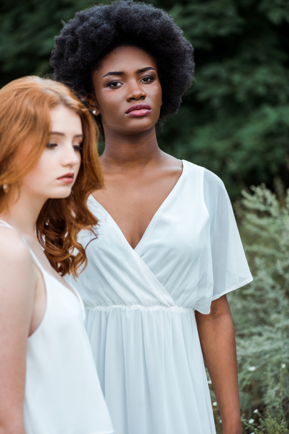 selective focus of attractive african american girl standing near redhead woman  - Fotoğraf, Görsel