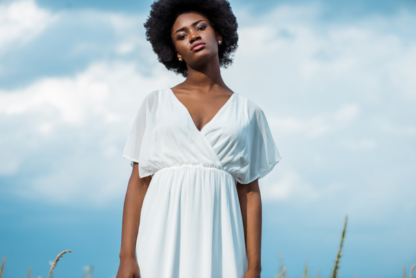 séduisante femme afro-américaine en robe blanche contre ciel bleu
  - Photo, image