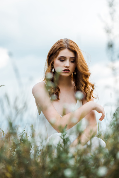 selective focus of upset young woman sitting in field  - Foto, Imagen