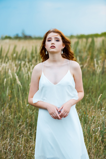 young redhead woman in white dress standing in field  - Foto, Imagem