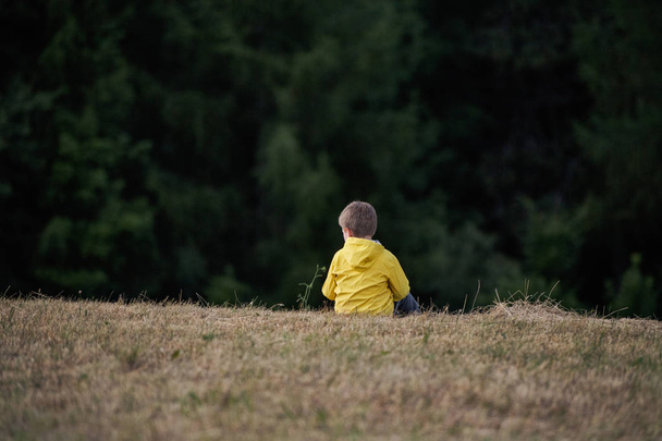 Rear view of school child sitting on field trip in nature, resting. - Foto, Bild