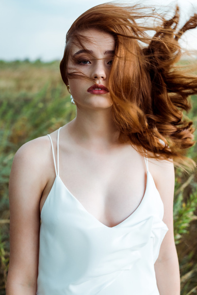 selective focus of pretty redhead woman in white dress looking at camera  - Fotoğraf, Görsel