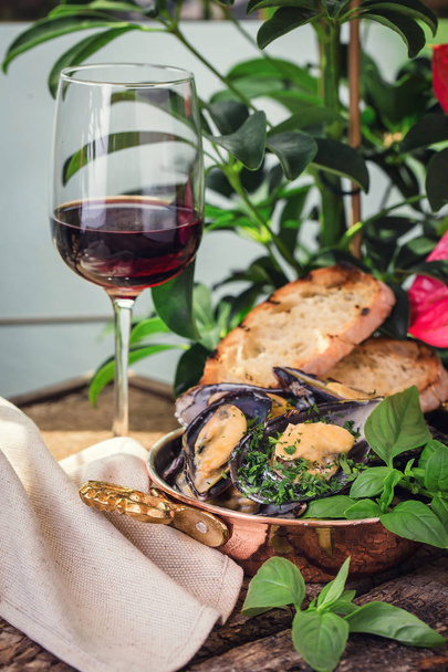  bir kadeh şarap ile ahşap bir tahta üzerinde pişmiş midye - Fotoğraf, Görsel