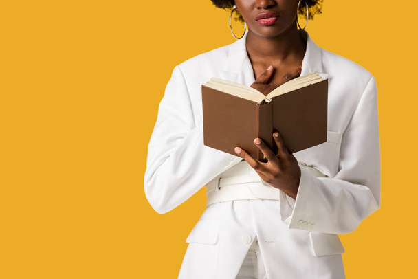 vista recortada de la mujer afroamericana sosteniendo libro aislado en naranja
  - Foto, imagen