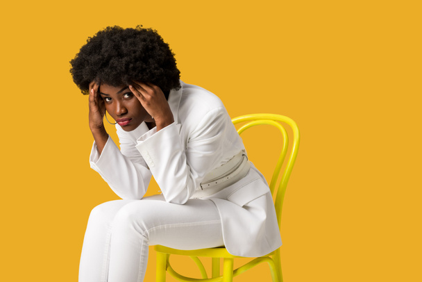 tired african american girl sitting on yellow chair isolated on orange  - Φωτογραφία, εικόνα