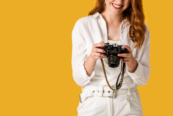cropped view of happy redhead girl holding digital camera isolated on orange  - Fotó, kép