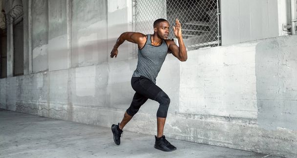 velocista atleta masculino afroamericano, corriendo a alta velocidad en el fondo de la ciudad de hormigón urbano con espacio de copia
 - Foto, Imagen