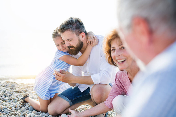 Familie van meerdere generaties op een vakantie zittend aan het meer, praten. - Foto, afbeelding