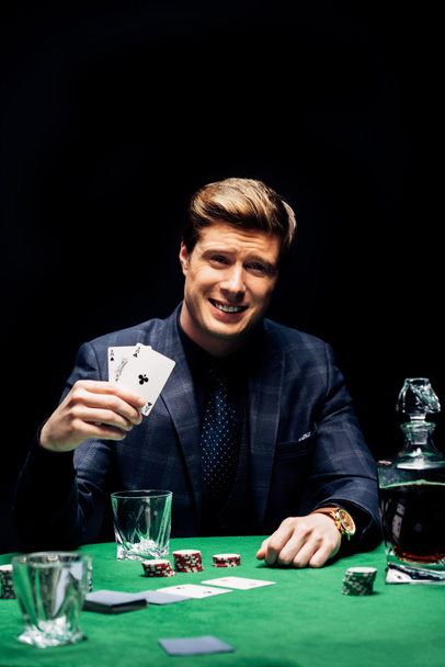 KYIV, UKRAINE - AUGUST 20, 2019: selective focus of happy man holding playing cards and playing poker isolated on black  - Foto, immagini