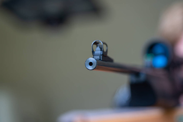 um jovem olha e aponta através do alcance do rifle de um ri preto
 - Foto, Imagem