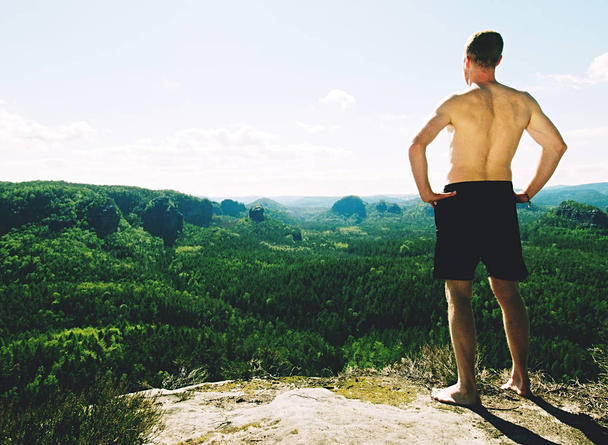 hombre caucásico alto sin camisa usar pantalones cortos negros descansa en pico de montaña
 - Foto, Imagen