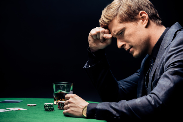 side view of frustrated man playing poker isolated on black - Photo, Image