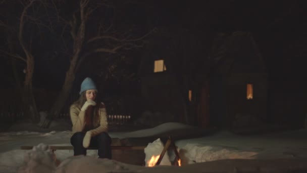 trauriges Mädchen sitzt allein im Dunkeln und blickt auf das Feuer. Allein ist sie kalt und gelangweilt. Ihr Lächeln verblasst. - Filmmaterial, Video
