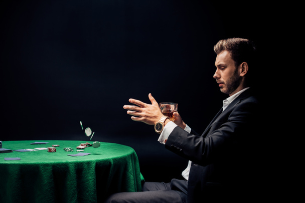 handsome man throwing in air poker chips on black  - Fotografie, Obrázek
