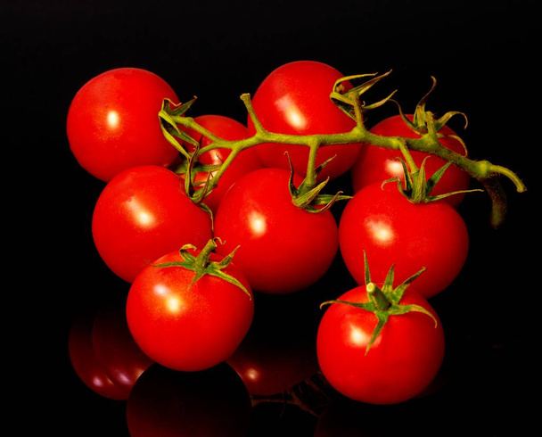 червоний помідор лежить на чорному фоні, овочі збирають
                               - Фото, зображення
