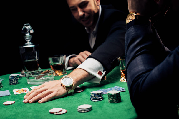 KYIV, UKRAINE - AUGUST 20, 2019: selective focus of man touching poker chips isolated on black - Photo, image