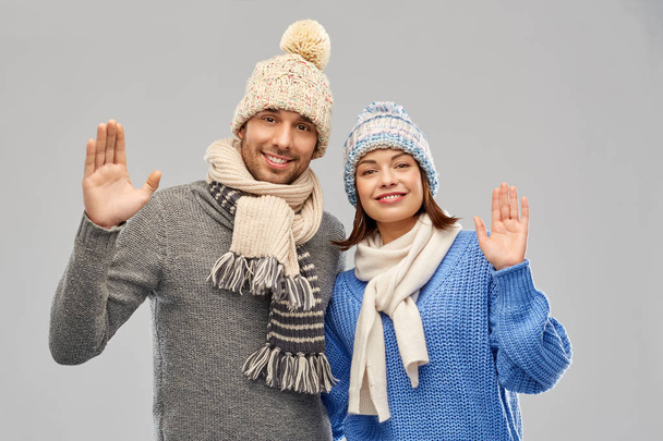 happy couple in winter clothes waving hands - Photo, Image