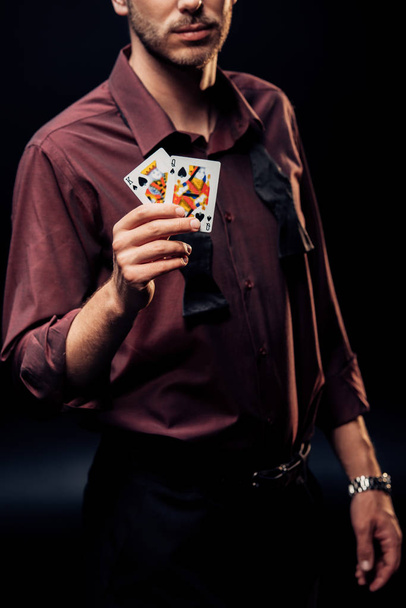 KYIV, UKRAINE - AUGUST 20, 2019: cropped view of man holding playing cards on black  - 写真・画像