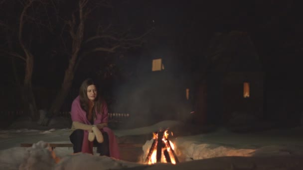 Smutná dívka sedí sama. Dívka je sama ve tmě a dívá se do ohně. Je studená a nudí se sama. Její úsměv pohasne.. - Záběry, video