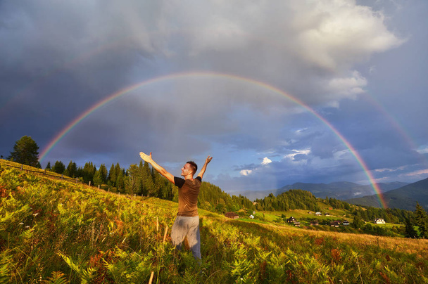 A happy man enjoys the rainbow in the mountains. - Photo, Image