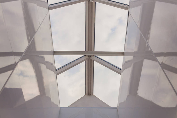 Mirando hacia el cielo azul nublado a través de la ventana del techo cuadrado moderno. - Foto, imagen