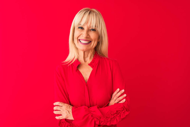 Femme d'âge moyen portant chemise élégante debout sur fond rouge isolé heureux visage souriant avec les bras croisés regardant la caméra. Personne positive
. - Photo, image