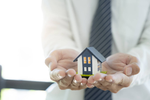 Business Man rękę trzymać model domu oszczędności mały dom. House - Zdjęcie, obraz