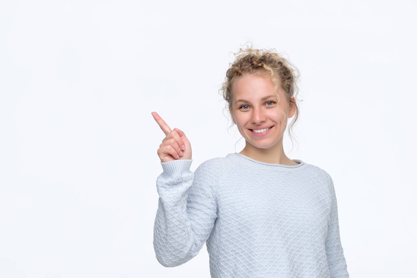 Girl with curly blonde hair smiling cheerfully and pointing with forefingers - Fotografie, Obrázek
