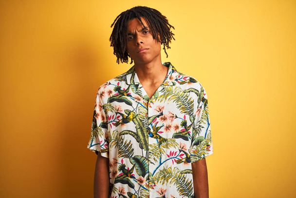 Afro man with dreadlocks on vacation wearing summer shirt over isolated yellow background skeptic and nervous, frowning upset because of problem. Negative person. - Foto, imagen