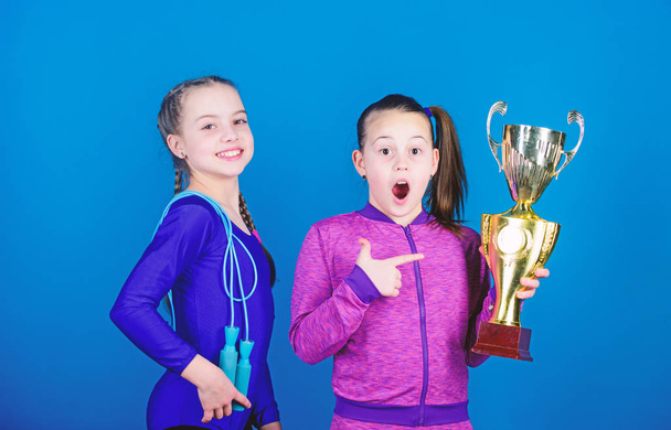Ansaittu palkinto. Tytöt urheilullinen lapset juhlivat voittoa. Urheilutyttöjä kultaisella pikarilla. Voittomestaruus. Joukkueemme ensimmäinen sija. Lapset voimistelijat urheilullinen lapset onnellinen mestareita. Urheilun saavutukset
 - Valokuva, kuva
