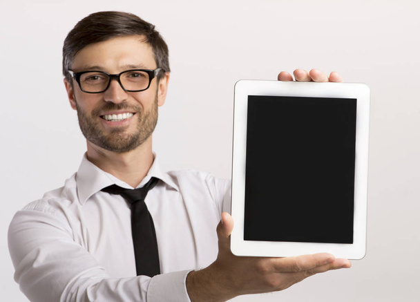 Lachende Business man toont lege tablet scherm op witte achtergrond - Foto, afbeelding