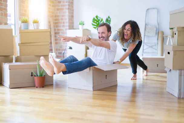 Middle age senior romantic couple having fun riding inside of cardboard, excited and smiling happy for moving to a new home - Photo, Image