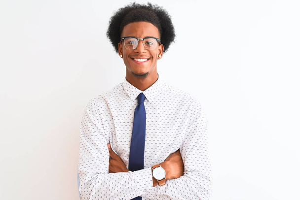 Joven hombre de negocios afroamericano con corbata y gafas sobre fondo blanco aislado cara feliz sonriendo con los brazos cruzados mirando a la cámara. Persona positiva
. - Foto, imagen