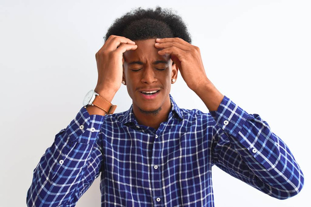 junger afrikanisch-amerikanischer Mann in lässigem Hemd, der vor isoliertem weißen Hintergrund steht und an Kopfschmerzen leidet, die verzweifelt und gestresst sind, weil Schmerzen und Migräne. Hände auf den Kopf. - Foto, Bild