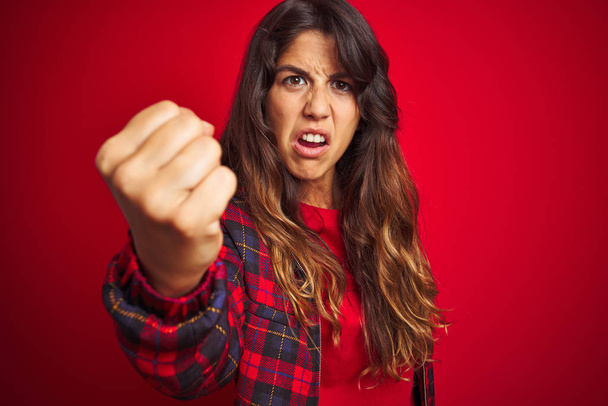 Young beautiful woman wearing casual jacket standing over red isolated background Showing middle finger doing fuck you bad expression, provocation and rude attitude. Screaming excited - Photo, Image