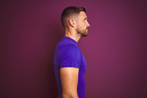 Giovane uomo che indossa casual viola t-shirt su sfondo lilla isolato cercando di lato, posa profilo relax con viso naturale con sorriso fiducioso
. - Foto, immagini