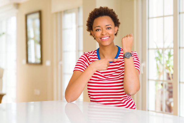 Jeune belle femme afro-américaine à la maison pressée de regarder le temps, l'impatience, contrariée et en colère pour retard de délai
 - Photo, image
